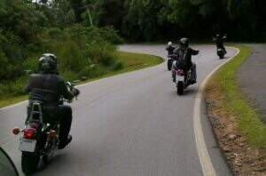 Quatro motos kustomizadas pelo Vento e a Taiana, todas em uma estrada arborizada