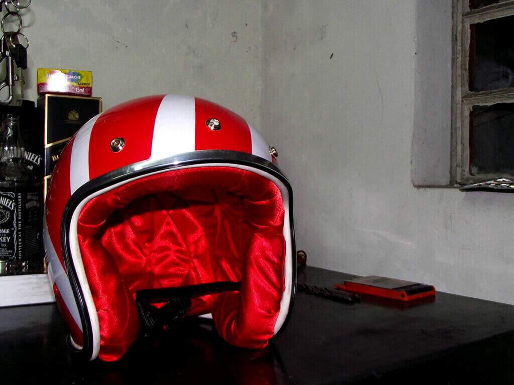 Capacete Old School com a frente aberta virado de frente mostrando o friso cromado e sua forração vermelha.