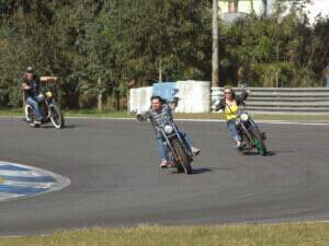 Vento e Tainana contornando a curva do miolo com suas motos, bem de frente para a câmera