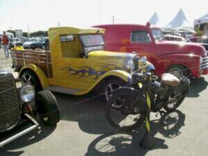 Uma caminhonete old school com uma moto em sua frente, expostas no evento.