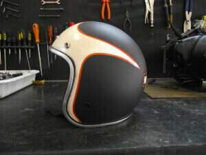 Capacete feito por nós em visto pela direita preto fosco e uma pintura branco semi-brilho dando um movimento do vento para traz, chegando ao logotipo da Harley-Davidson.