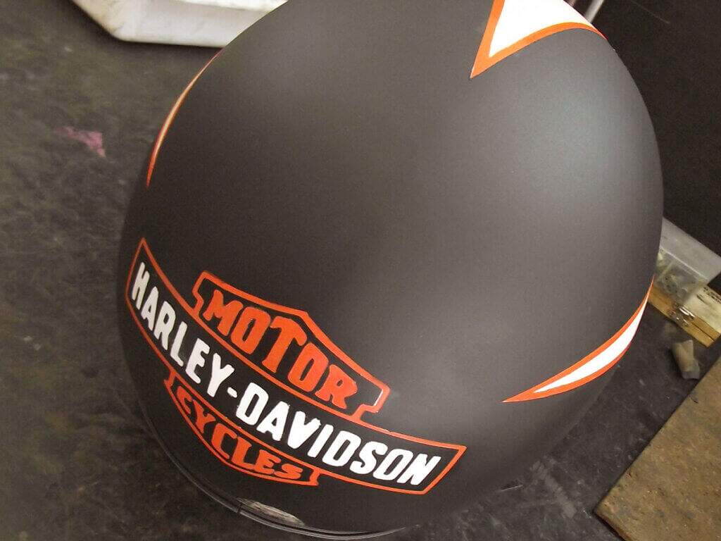 Capacete feito por nós em preto fosco e uma pintura branco semi-brilho dando um movimento do vento para traz, chegando ao logotipo da Harley-Davidson.