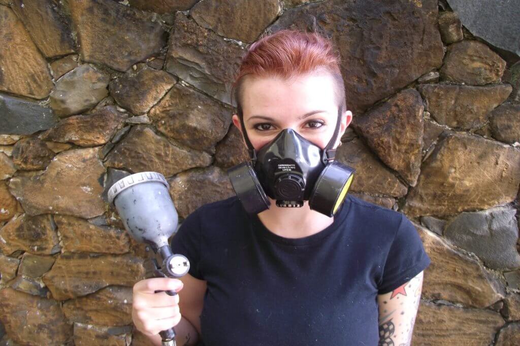 Taiana com seu equipamento de trabalho: Mascara de pintura, pistola e habilidade. Ela será a responsável pela pintura da Honda XR 250 Tornado que transformaremos em uma Tracker Old School.