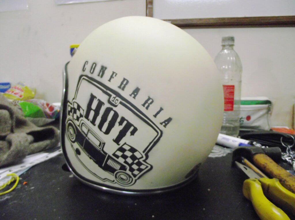 Capacete da confraria do Hot de Curitiba. Capacete branco de lado exibindo o logo em preto.